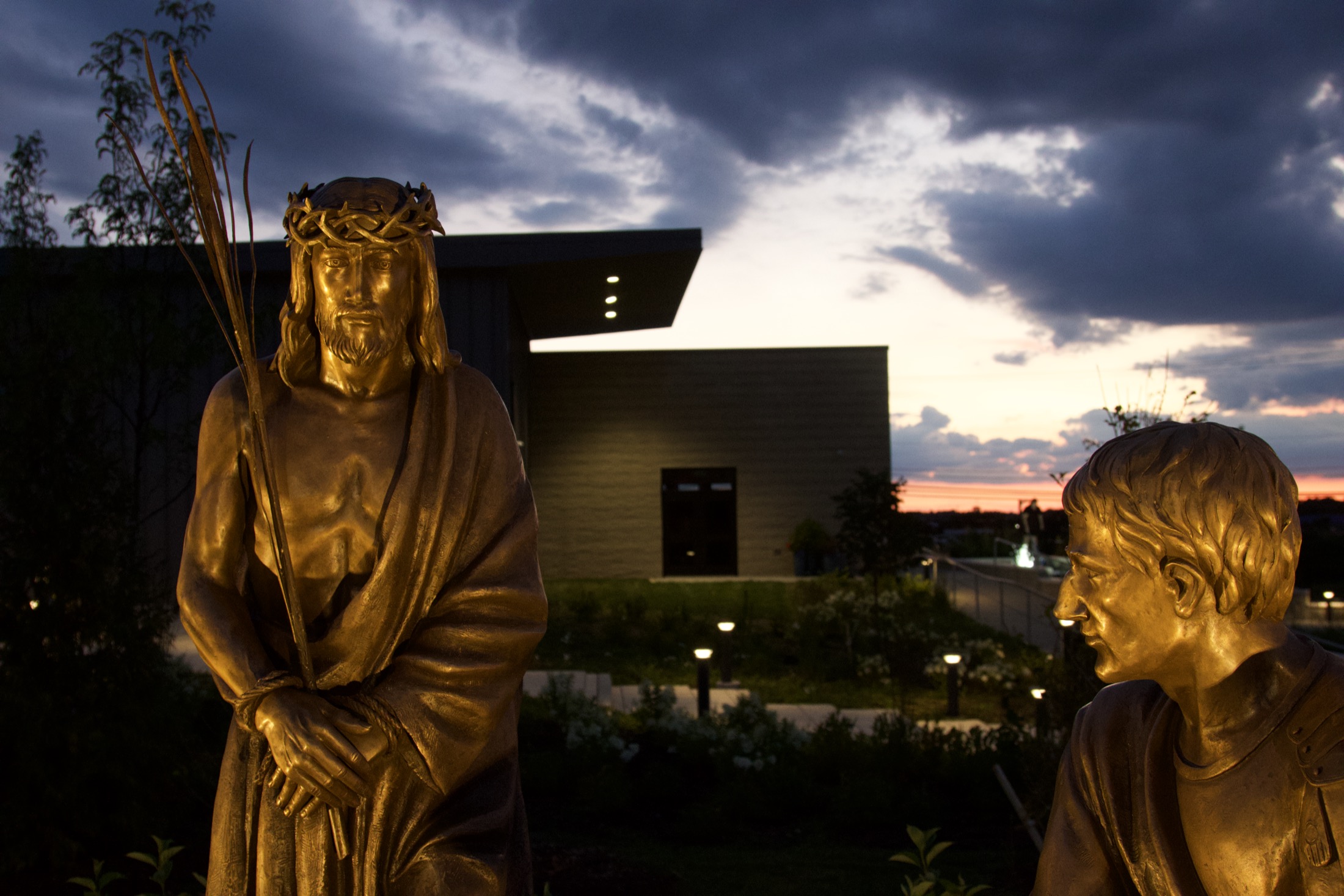 A close profile of a bronze figure of Christ’s face, caught in golden-hour light.