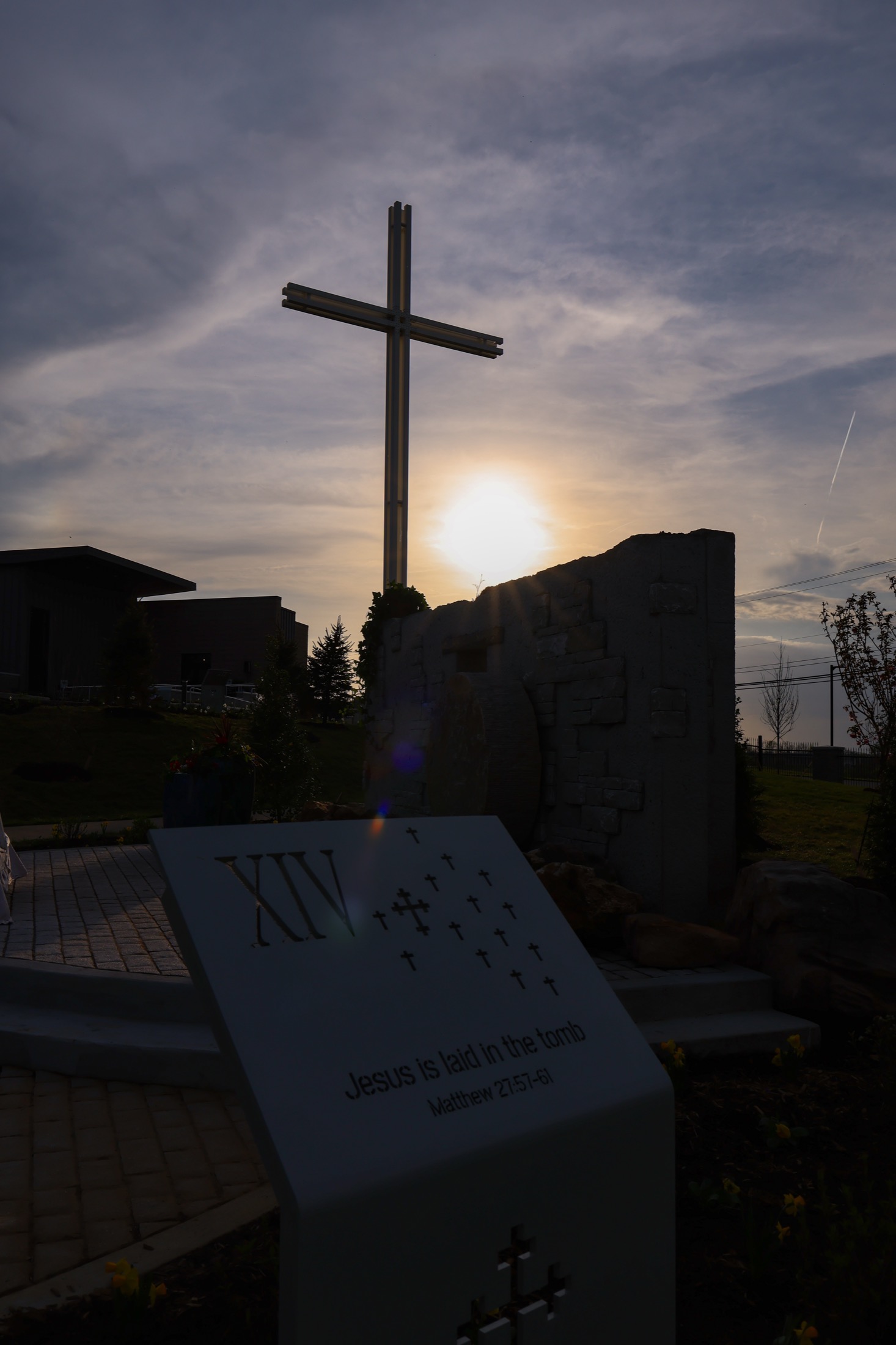 A cross catching a burst of golden-hour sunlight against a clear sky.