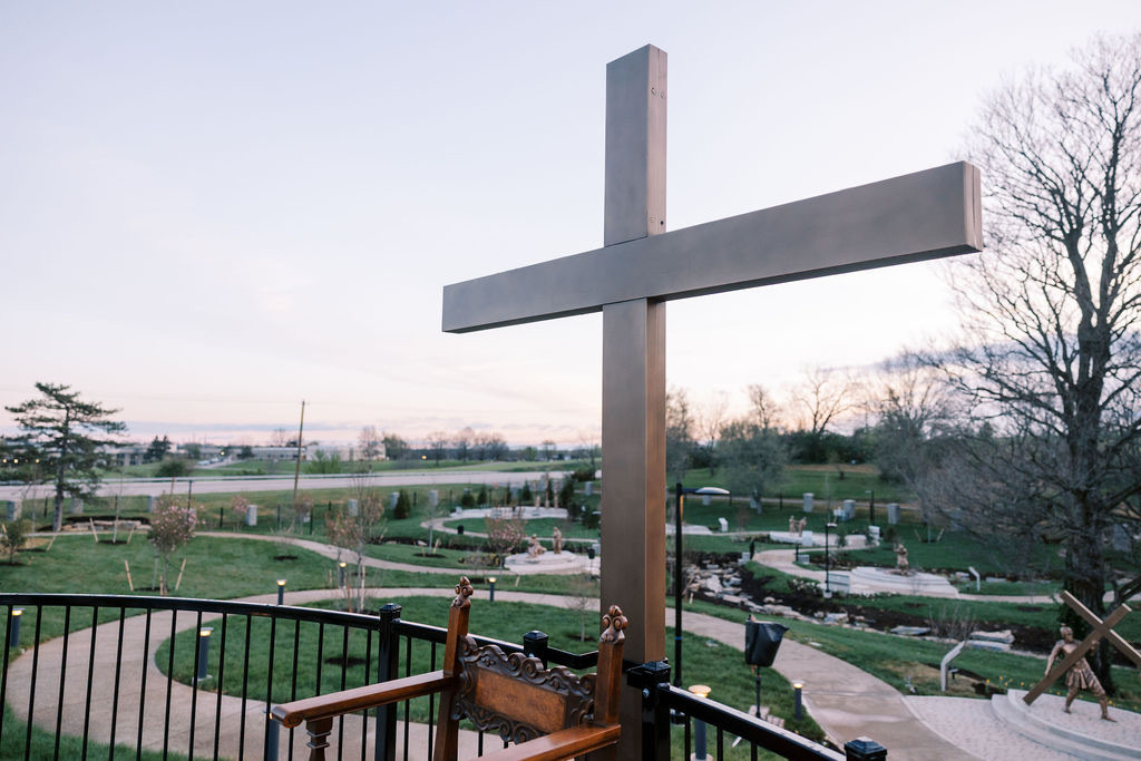 The monumental cross overlooking the garden path at dusk.