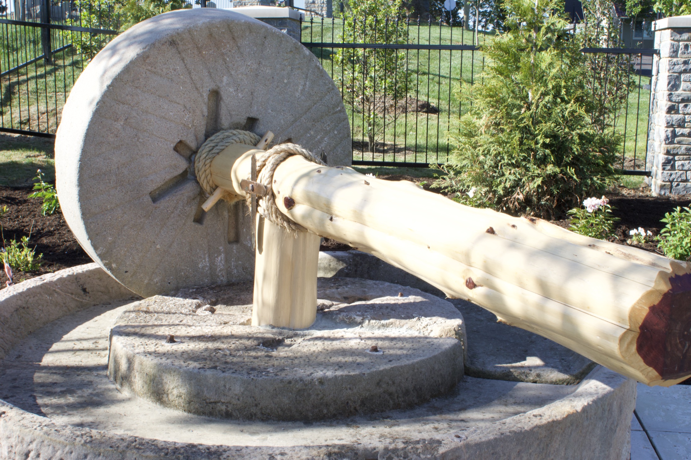 The olive press feature set within a planted garden bed near the start of the Stations path.