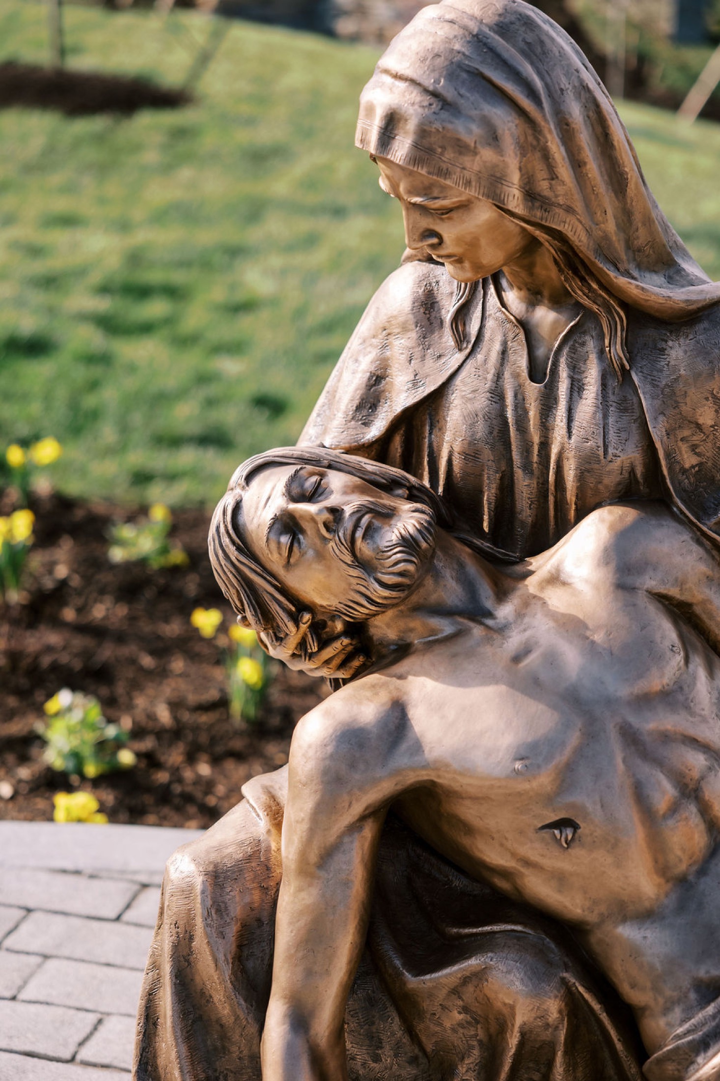 A close view of the bronze Pietà, Mary cradling the body of Christ.