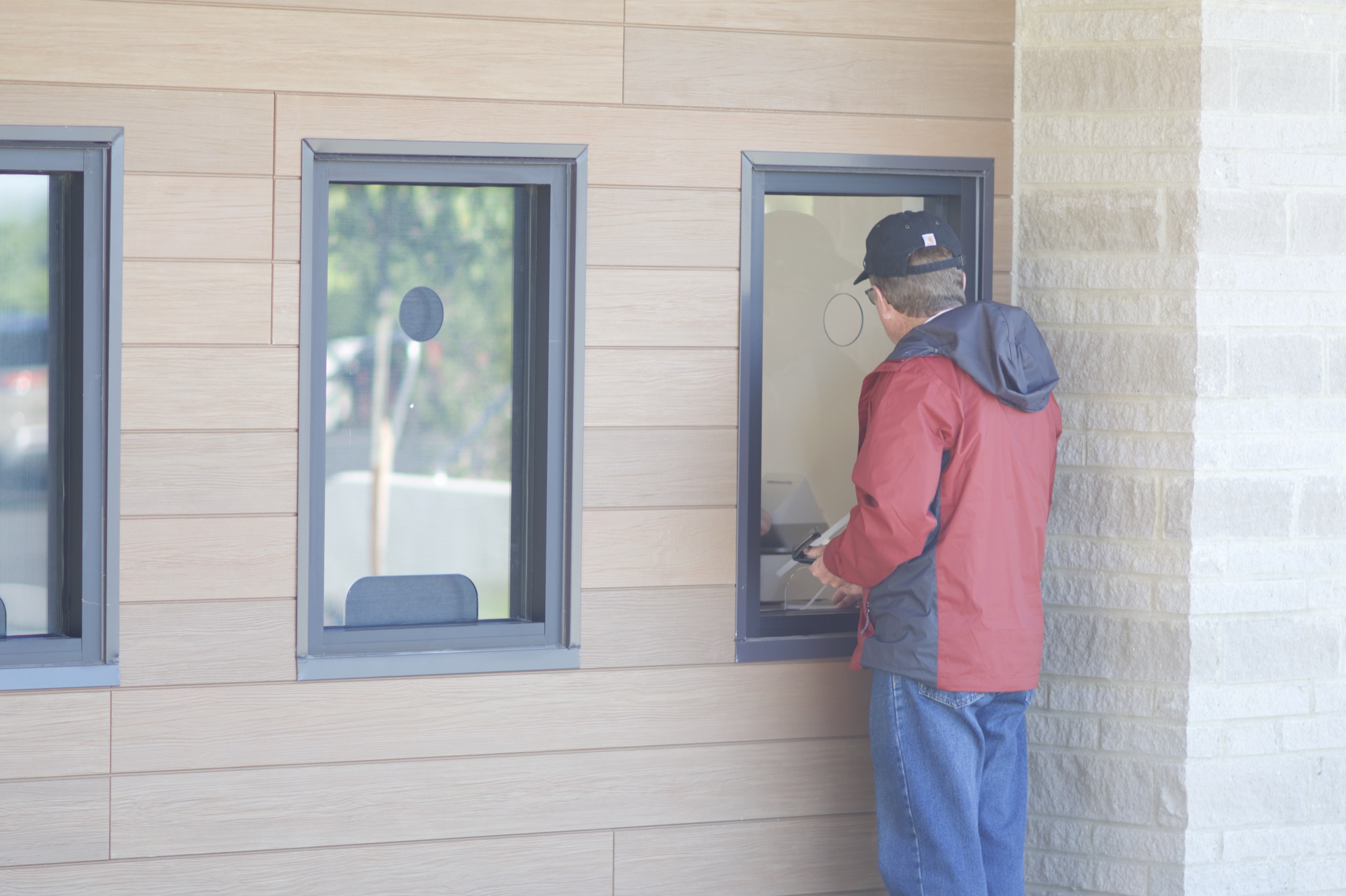 A visitor leans toward the ticket window at the Welcome Center on a sunlit afternoon.